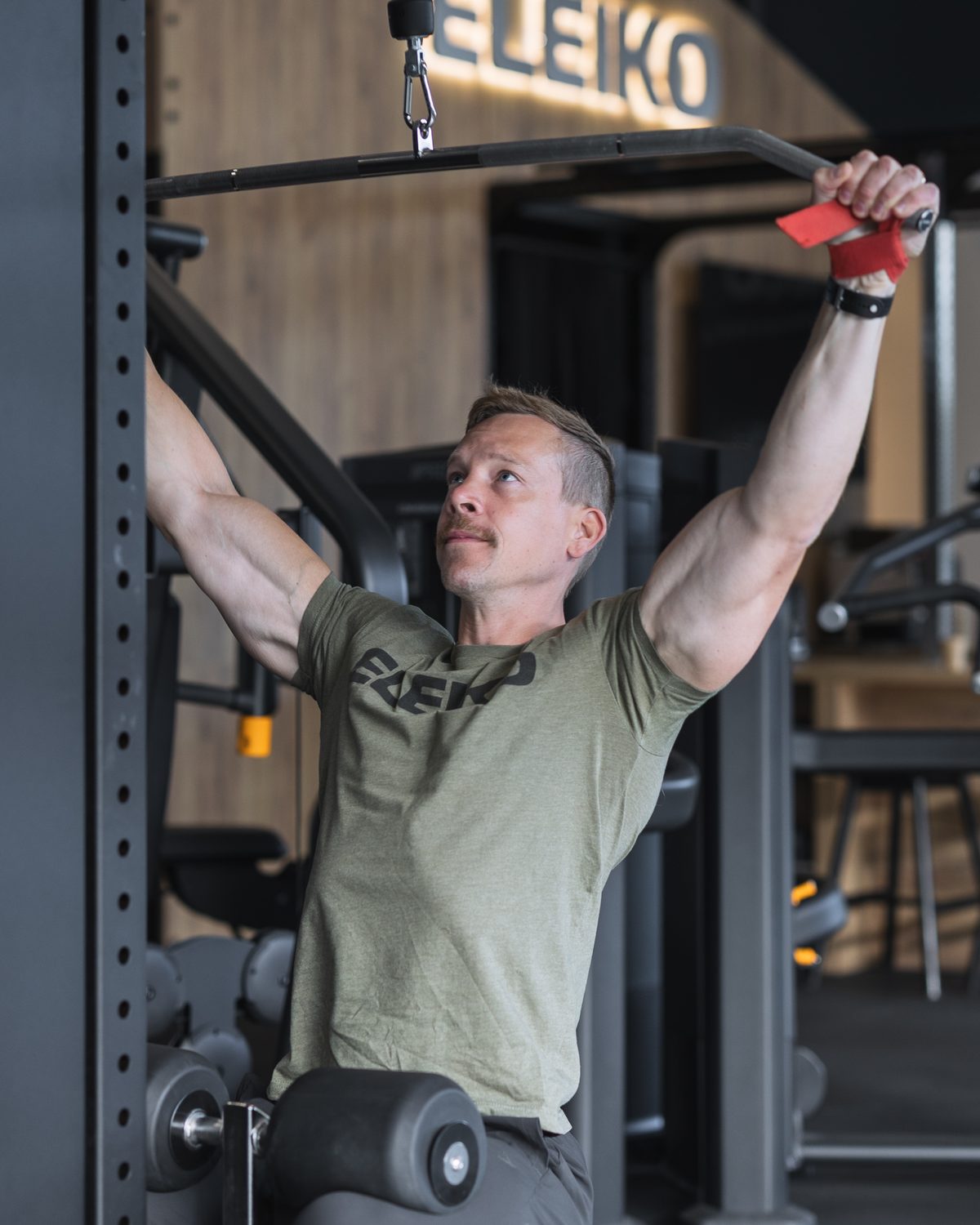 Oscar Björk at the top of a lat pulldown rep, arms fully extended overhead.
