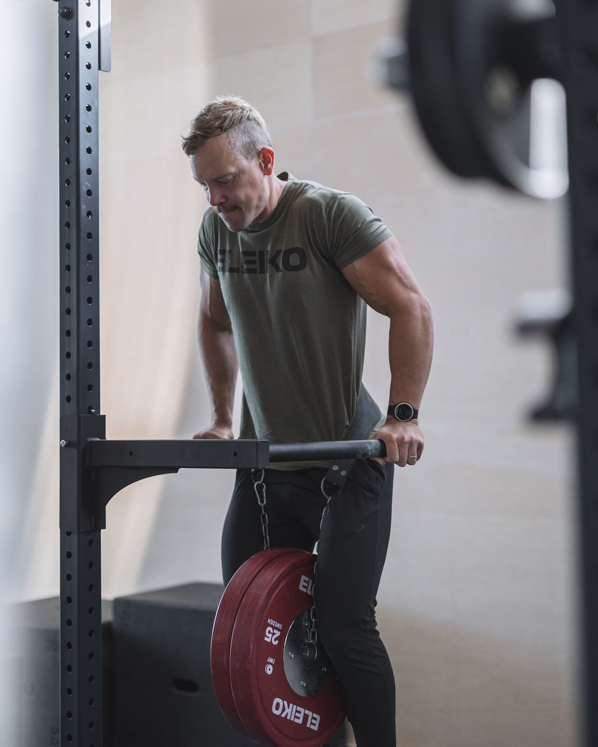 Oscar Björk performing a weighted dip in a rack, with Eleiko plates hanging from a dip belt.